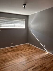 Small room painted warm gray with white trim, glass ceiling light and natural oak hardwood floors