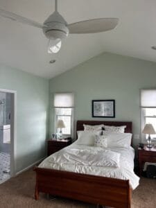 Master bedroom with walls painted pale seafoam green under a vaulted white ceiling with a cherry sleigh bed