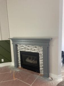Fireplace mantel freshly painted slate gray with light greige walls and olive green accent wall paneling