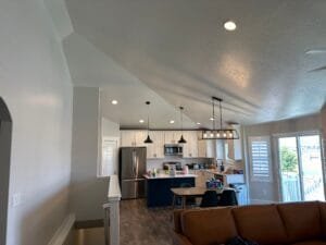 Open-concept living room and kitchen with freshly painted light gray walls and vaulted textured ceiling