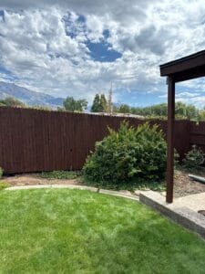 Dark brown stained backyard fence and matching patio cover posts with mountains behind
