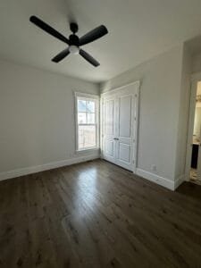 Bedroom freshly painted light gray with white closet doors, window trim and baseboards