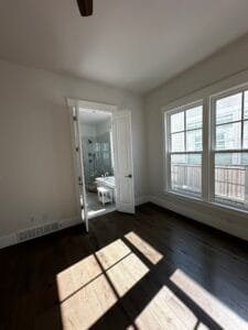 Primary bedroom painted soft white with white trim and double doors opening to an ensuite bathroom