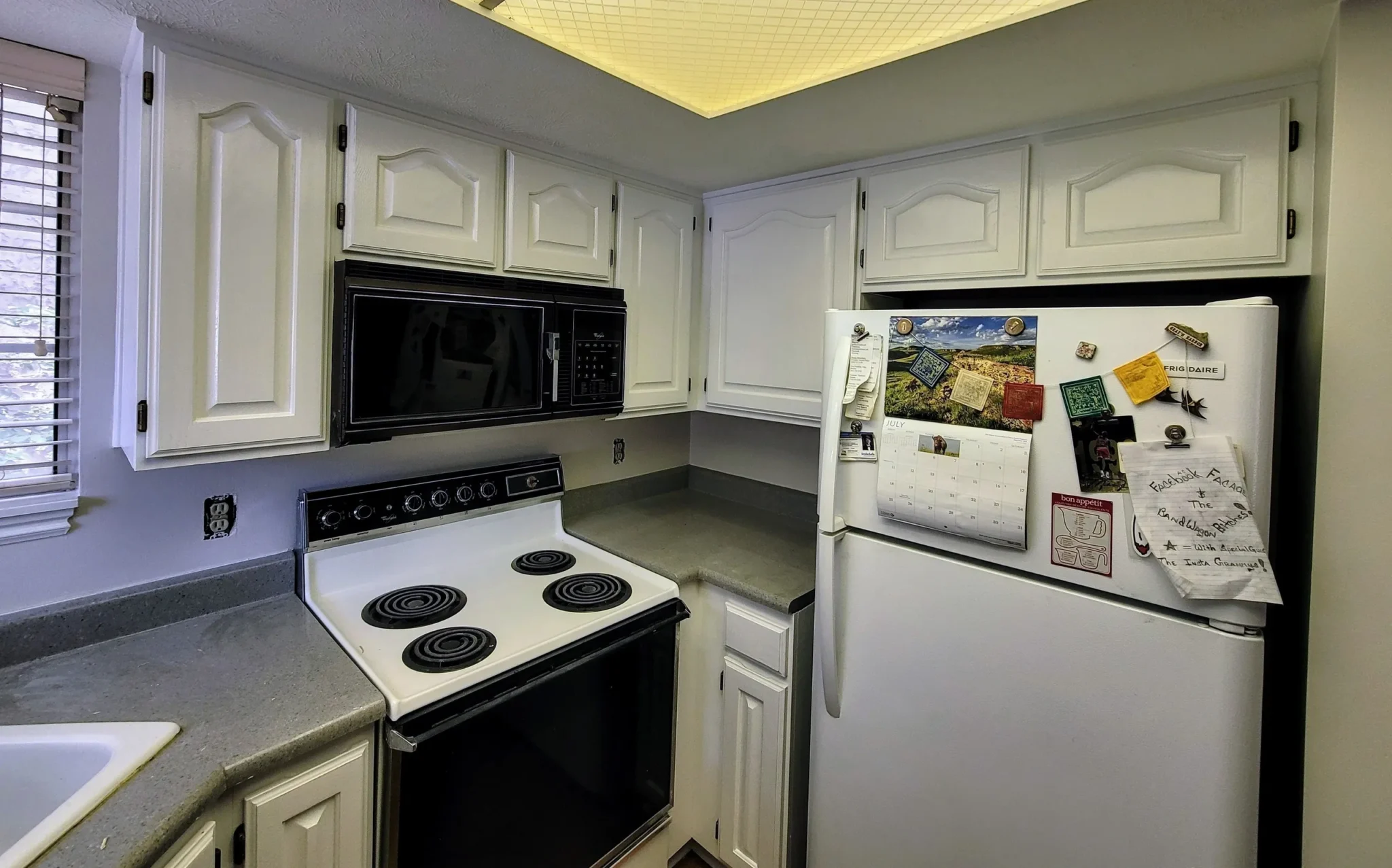 Small kitchen with cathedral arch cabinet doors painted white and gray laminate countertops
