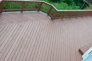 Overhead view of an angled-board deck with solid brown stain on boards and railing