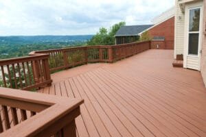 Large hillside deck and railing in solid russet brown stain overlooking a wooded valley