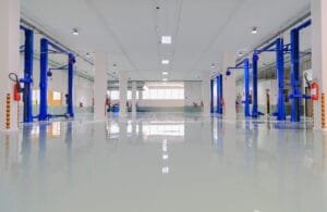 Auto service bay with a glossy white epoxy floor coating, white walls and blue vehicle lifts