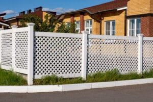 White diagonal lattice fence panels along a street in front of brick homes