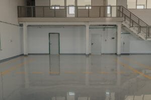 Warehouse with a gray epoxy floor coating and yellow safety line markings under a steel mezzanine