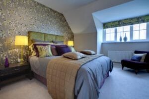 Bedroom with a floral wallpaper accent wall behind the bed and soft gray painted walls