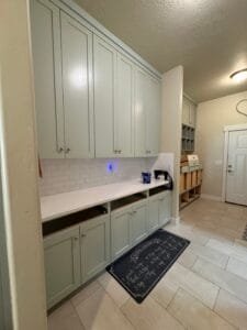 Butler's pantry with tall shaker cabinets painted pale sage green and a white subway tile backsplash