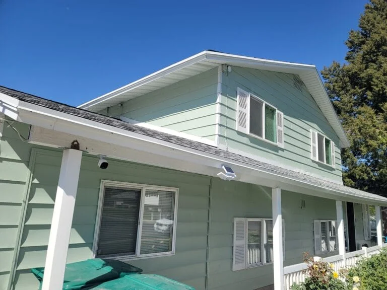 Two-story home exterior freshly painted mint green with white trim, shutters and porch posts