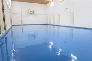 Gymnasium with a freshly applied high-gloss blue epoxy floor coating and white painted walls