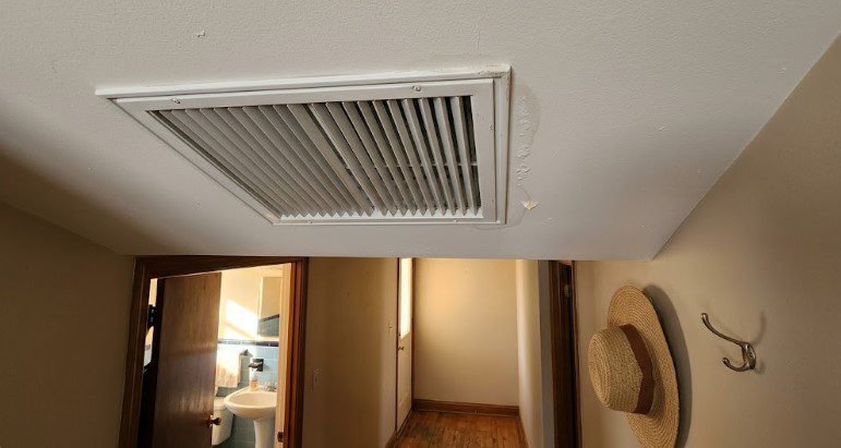 Large evaporative cooler register in a hallway ceiling outside a bathroom